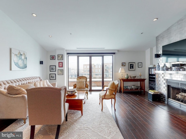 living room featuring dark wood-style floors, recessed lighting, a brick fireplace, and vaulted ceiling