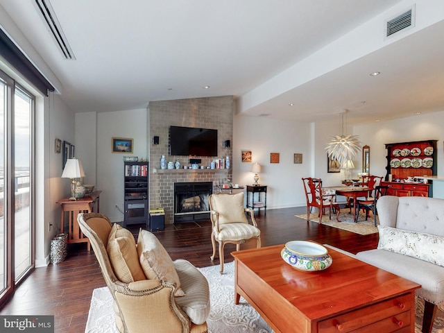 living room featuring lofted ceiling, dark wood-type flooring, a fireplace, and visible vents