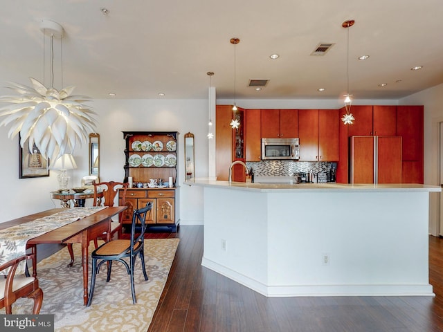 kitchen with decorative backsplash, dark hardwood / wood-style flooring, paneled fridge, sink, and decorative light fixtures