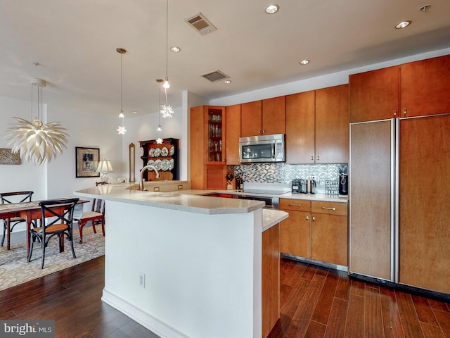 kitchen with light countertops, stainless steel microwave, visible vents, glass insert cabinets, and paneled refrigerator