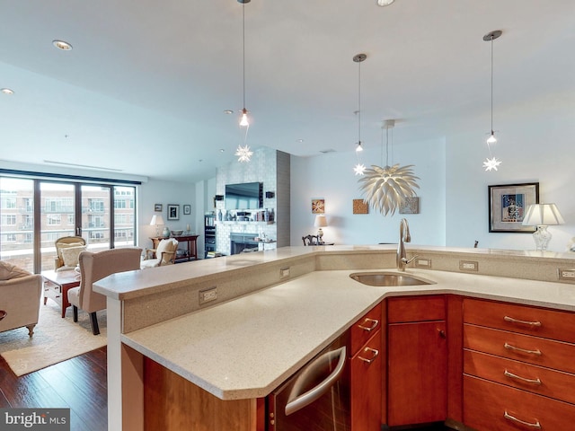 kitchen featuring light stone counters, sink, hanging light fixtures, and dark wood-type flooring