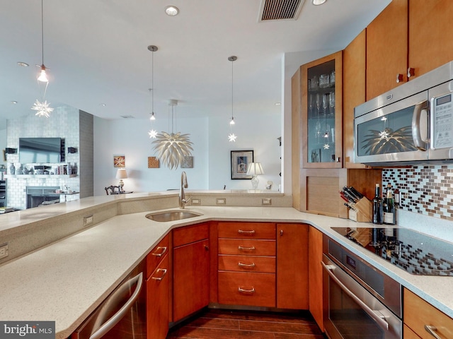 kitchen featuring hanging light fixtures, sink, decorative backsplash, appliances with stainless steel finishes, and kitchen peninsula