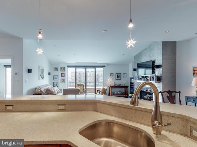 kitchen featuring open floor plan, hanging light fixtures, a sink, and lofted ceiling