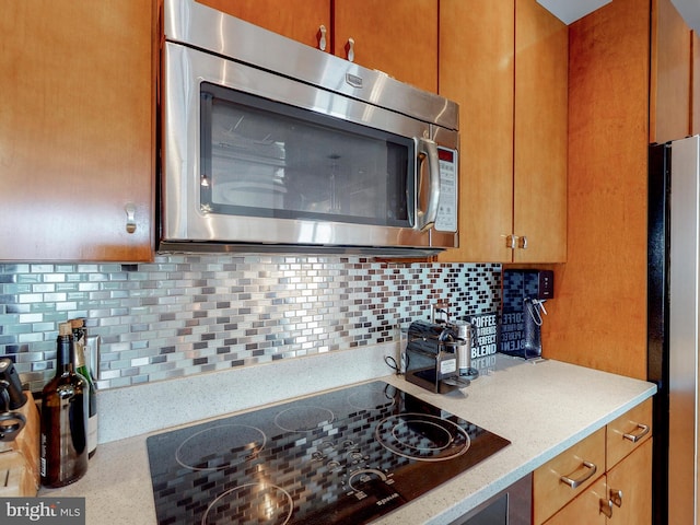 kitchen with light stone countertops, stainless steel appliances, and tasteful backsplash