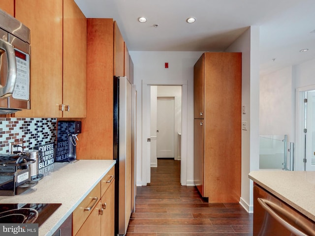 kitchen with dark hardwood / wood-style flooring, light stone countertops, stainless steel appliances, and tasteful backsplash