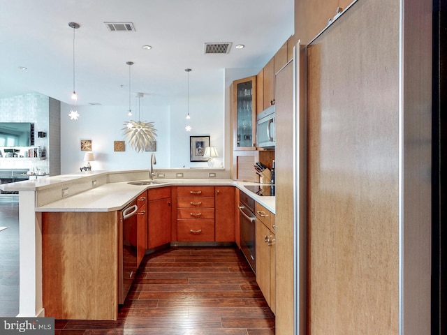 kitchen with sink, hanging light fixtures, dark wood-type flooring, kitchen peninsula, and appliances with stainless steel finishes