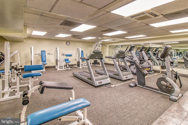 workout area with a paneled ceiling, visible vents, and baseboards