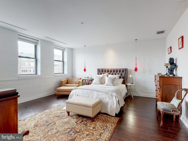 bedroom featuring dark wood-type flooring and brick wall