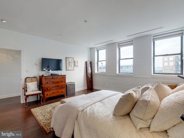 bedroom featuring hardwood / wood-style floors and brick wall