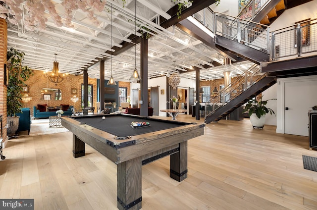 recreation room featuring brick wall, billiards, an inviting chandelier, and light hardwood / wood-style flooring