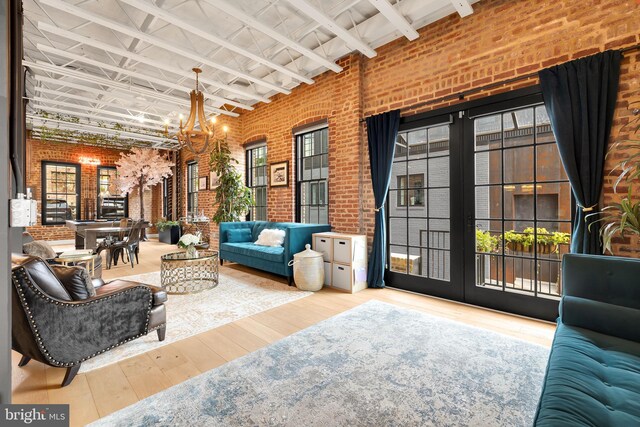 interior space with brick wall, an inviting chandelier, beam ceiling, and hardwood / wood-style flooring