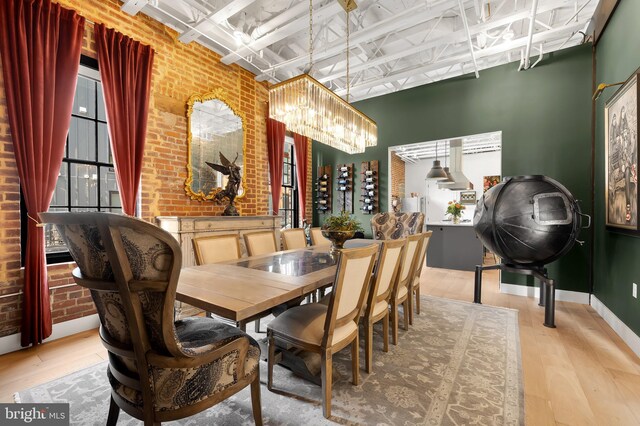 dining space with an inviting chandelier, light hardwood / wood-style floors, and brick wall