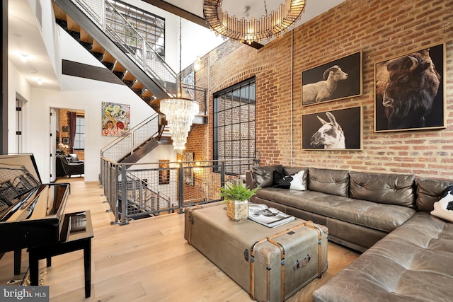 living area with an inviting chandelier, brick wall, stairway, and wood finished floors