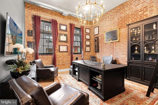 office area featuring a chandelier and brick wall