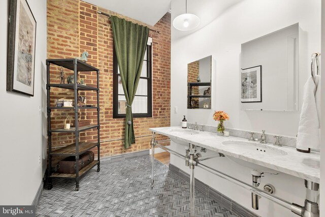 bathroom featuring vanity and brick wall