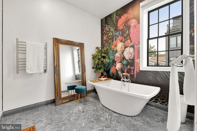 full bath featuring a soaking tub, baseboards, and wallpapered walls