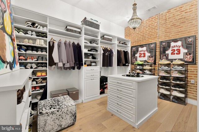 walk in closet with light hardwood / wood-style flooring