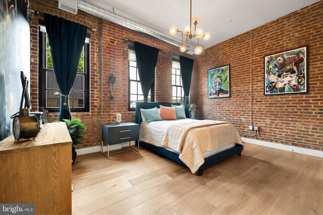 bedroom featuring brick wall, a notable chandelier, multiple windows, and light hardwood / wood-style floors