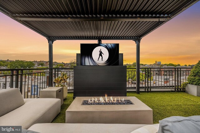 patio terrace at dusk featuring a balcony and an outdoor fire pit