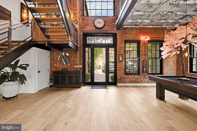 foyer with light hardwood / wood-style flooring, a wealth of natural light, brick wall, and pool table