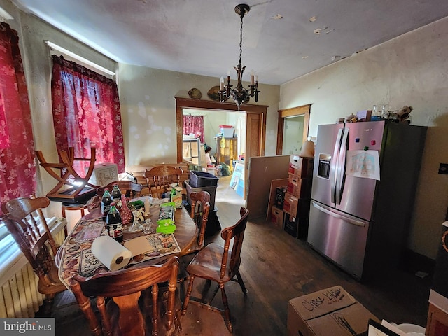 dining space with radiator heating unit, hardwood / wood-style floors, and a chandelier