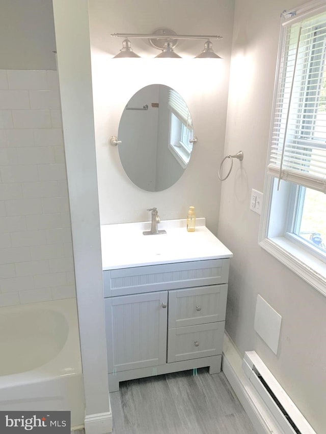 bathroom with a wealth of natural light, a baseboard radiator, vanity, and shower with separate bathtub