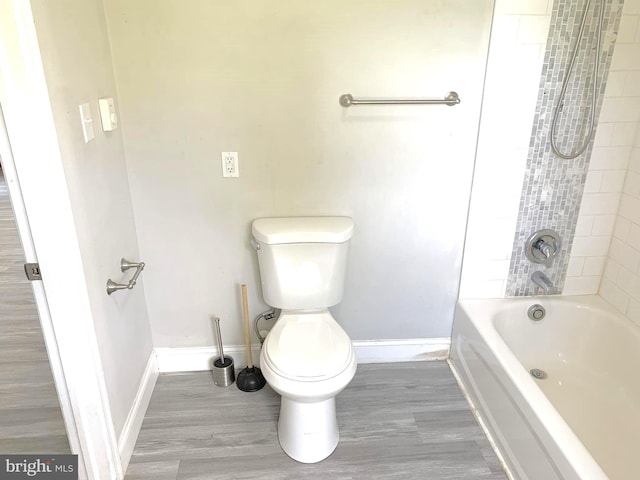 bathroom with wood-type flooring, toilet, and tiled shower / bath