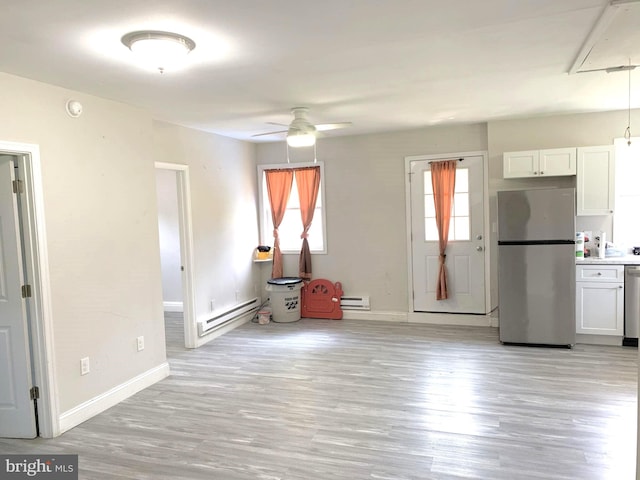 interior space featuring a baseboard heating unit, a healthy amount of sunlight, ceiling fan, and light wood-type flooring