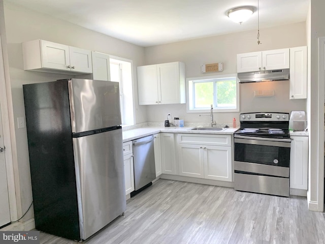 kitchen with stainless steel appliances, sink, white cabinets, and light hardwood / wood-style floors