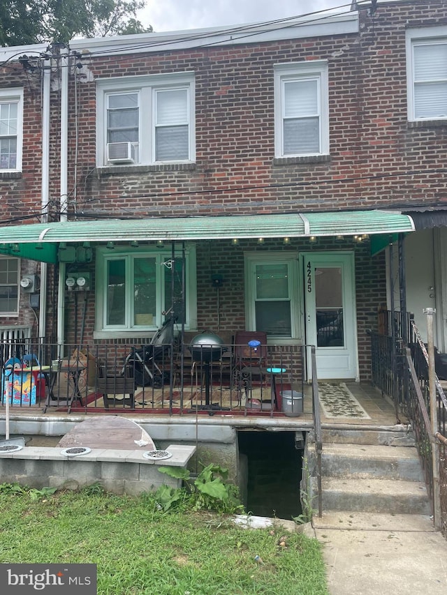 multi unit property with a porch, cooling unit, and brick siding