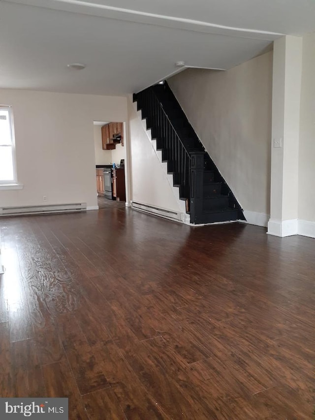 unfurnished living room with dark wood-style floors, baseboards, baseboard heating, and stairs