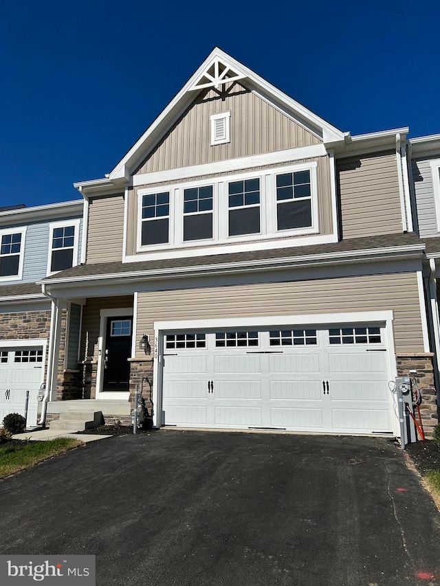 view of front of house featuring aphalt driveway, stone siding, board and batten siding, and a garage