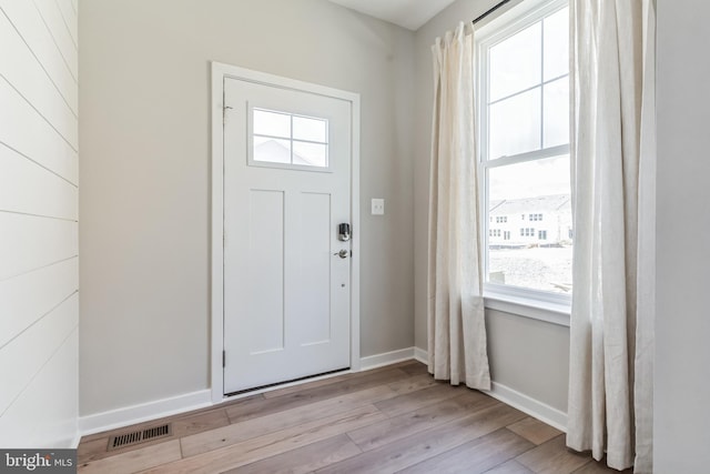 foyer entrance with visible vents, baseboards, and light wood-style floors