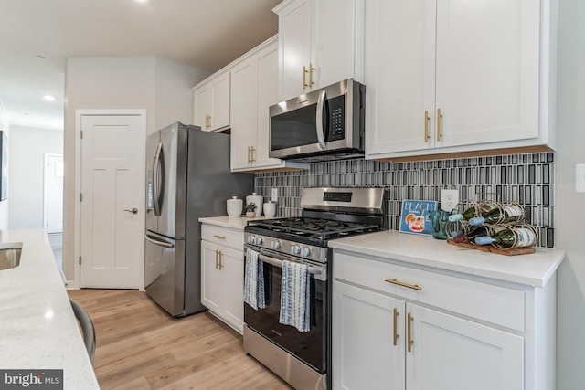 kitchen featuring backsplash, light wood-style flooring, white cabinetry, and stainless steel appliances