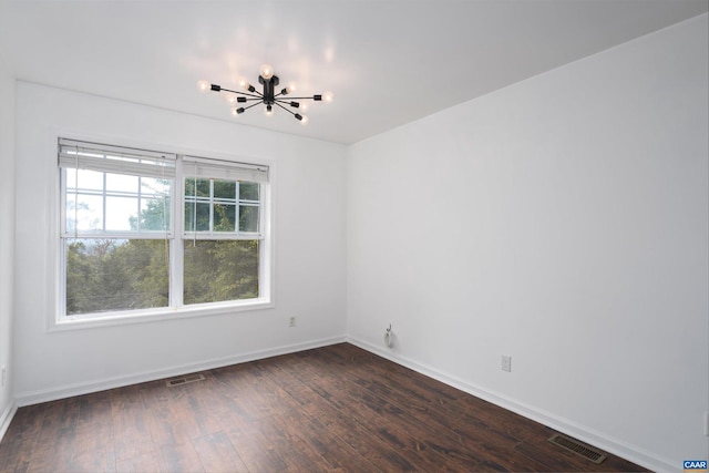 unfurnished room with baseboards, dark wood-style flooring, visible vents, and an inviting chandelier