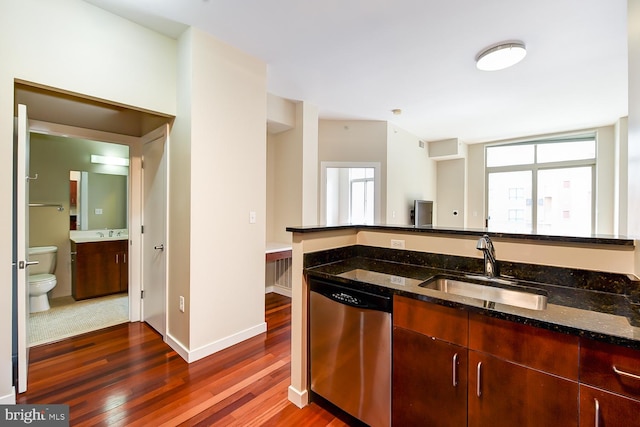 kitchen featuring dark stone counters, stainless steel dishwasher, sink, and dark wood-type flooring