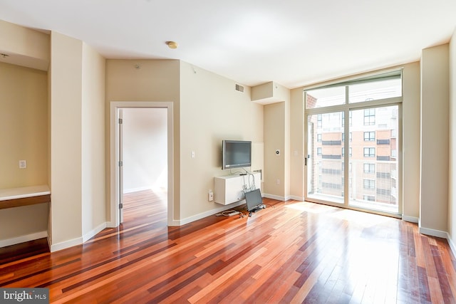 unfurnished living room featuring floor to ceiling windows and dark hardwood / wood-style floors