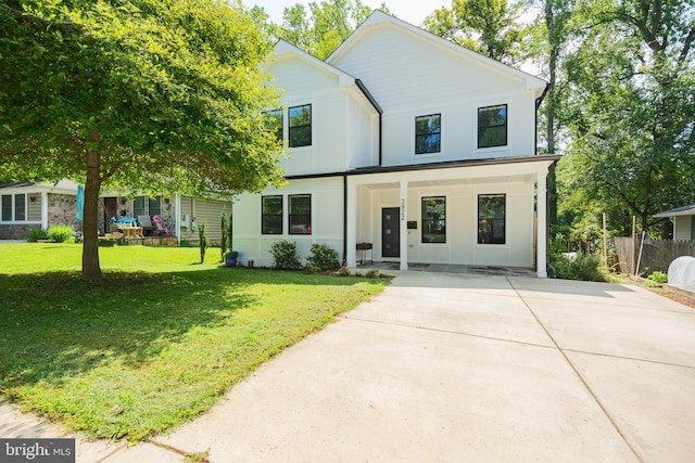 view of front of home featuring concrete driveway, fence, a front lawn, and stucco siding