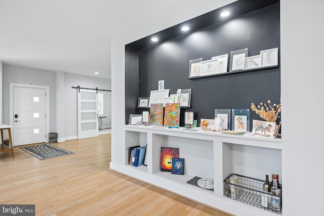 interior space featuring a barn door, baseboards, wood finished floors, and recessed lighting