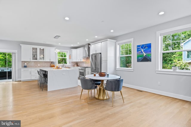 kitchen with high end appliances, white cabinets, glass insert cabinets, a center island, and light countertops