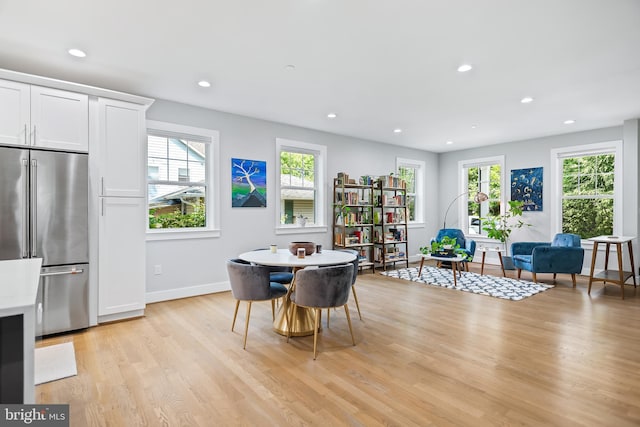 dining room with baseboards, light wood finished floors, plenty of natural light, and recessed lighting