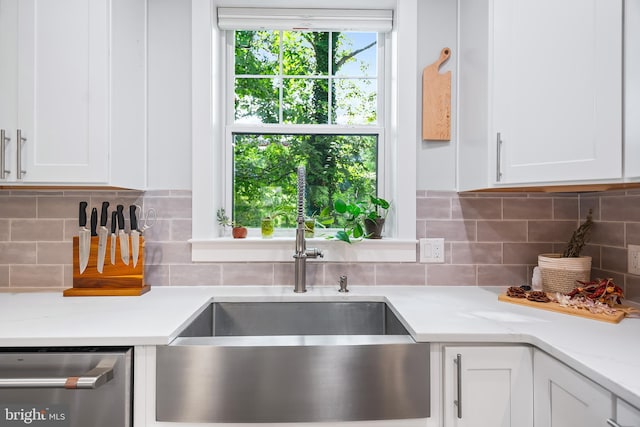 kitchen featuring light stone counters, white cabinetry, a sink, and stainless steel dishwasher