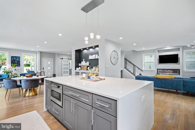 kitchen featuring a barn door, open floor plan, a center island, hanging light fixtures, and light countertops