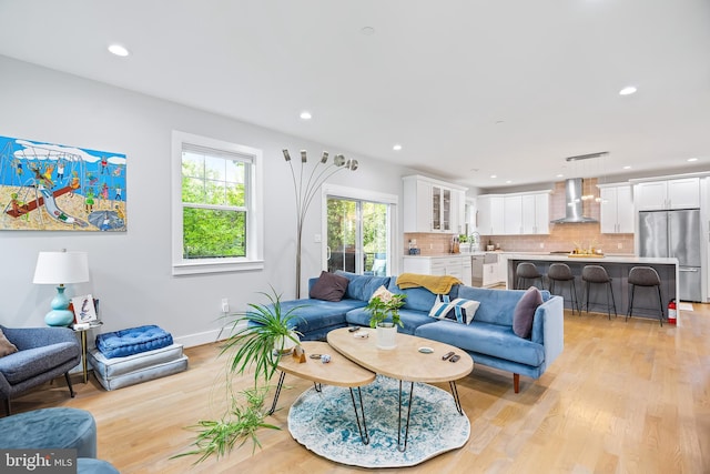 living room with recessed lighting, light wood-style flooring, and baseboards