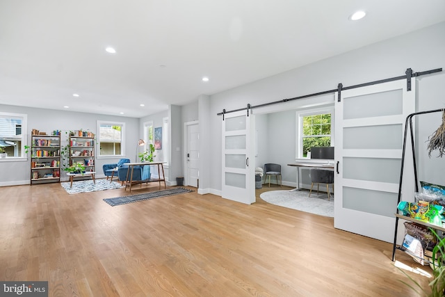 interior space with a barn door, plenty of natural light, light wood-style flooring, and recessed lighting