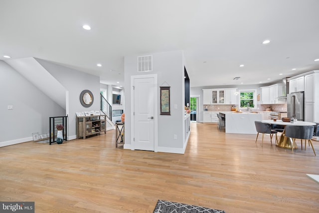 living area with recessed lighting, visible vents, baseboards, light wood-style floors, and stairway