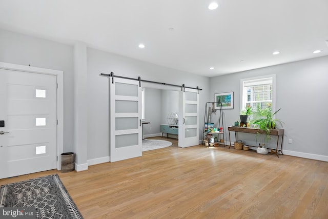 foyer entrance featuring baseboards, a barn door, recessed lighting, and light wood-style floors