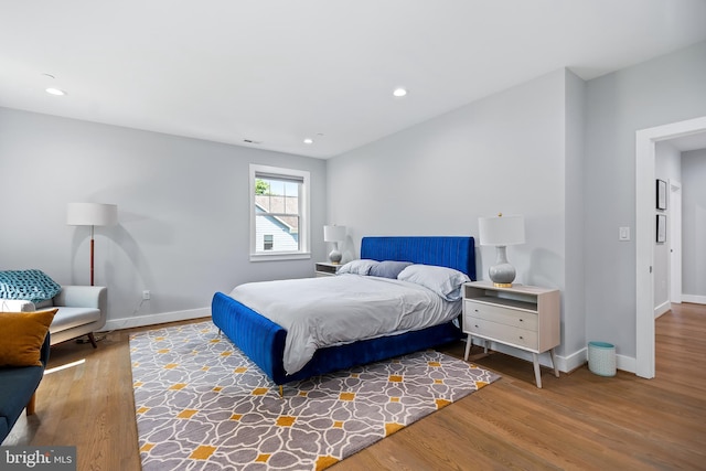 bedroom featuring baseboards, wood finished floors, and recessed lighting