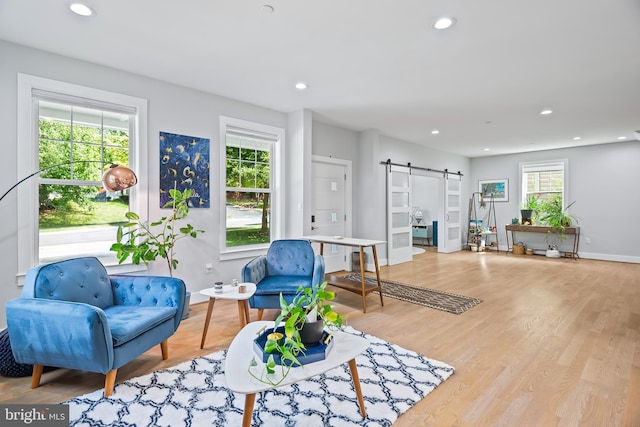 living area with plenty of natural light, a barn door, light wood-style flooring, and recessed lighting