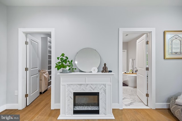 living area featuring light wood-type flooring, a fireplace, and baseboards